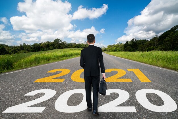 El viaje del Año Nuevo 2021 y el concepto de visión futura. Hombre de negocios viajando por la carretera que conduce a la celebración del feliz año nuevo a principios de 2021 para un comienzo nuevo y exitoso.