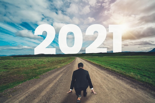 El viaje del Año Nuevo 2021 y el concepto de visión futura. Hombre de negocios viajando por la carretera que conduce a la celebración del feliz año nuevo a principios de 2021 para un comienzo nuevo y exitoso.