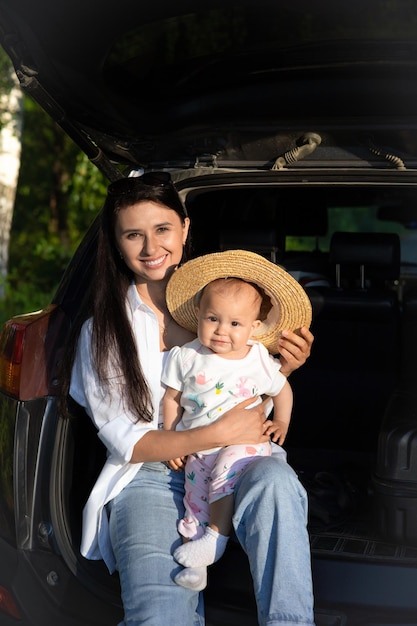 Foto viaje en automóvil viajar con un niño en automóvil madre e hija se sientan en un automóvil con el maletero abierto