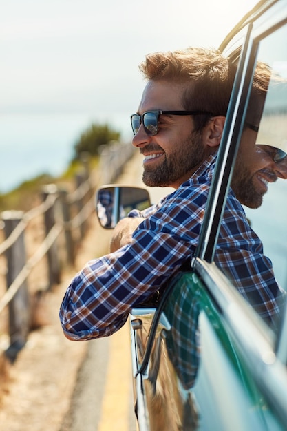 Foto viaje por carretera y hombre con una sonrisa en la conducción de automóviles para aventuras de vacaciones de verano y vacaciones ventana de transporte y hombre feliz en vehículo de motor para un viaje de libertad y relajarse junto al océano