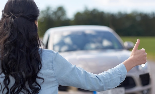 viaje por carretera, viaje, gesto y concepto de personas - mujer haciendo autostop y deteniendo el camión con gesto de aprobación en el campo