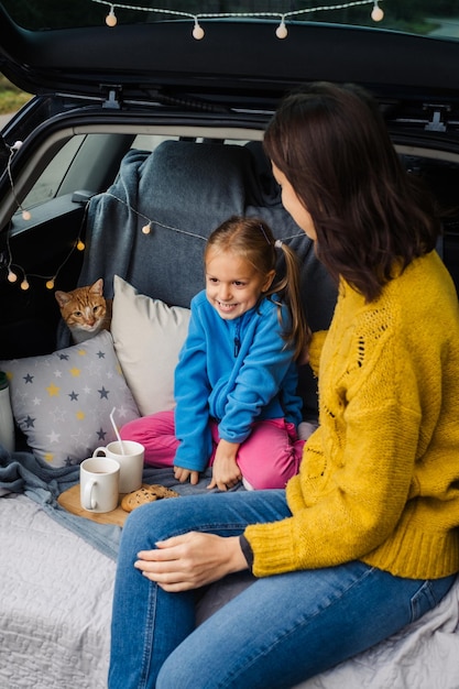 Viaje familiar por carretera con mascota sentada en el baúl del auto y comiendo comida sabrosa