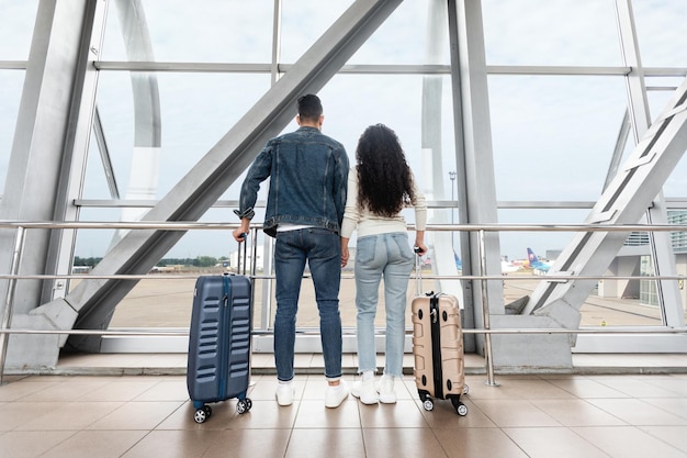 Viaje juntos vista traseira do jovem casal esperando o voo no aeroporto