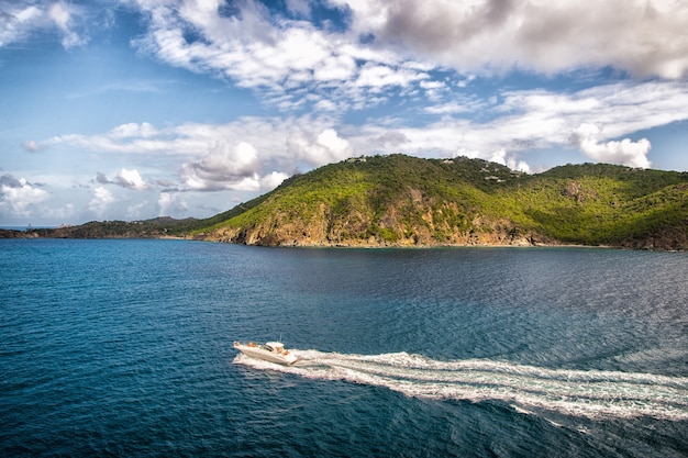 Viaje en lancha motora en el mar azul en el cielo nublado en gustavia, st barts. Viajar en barco, pasión por los viajes. Vacaciones de verano en una isla tropical. Transporte de agua y embarcación. Hermoso paisaje con montañas.