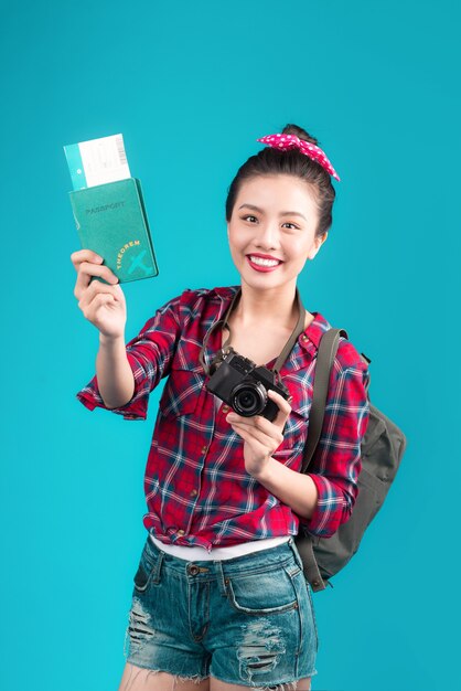 Foto viaje de mujer. viajero asiático hermoso joven que sostiene el pasaporte y el boleto aéreo que se coloca sobre azul.