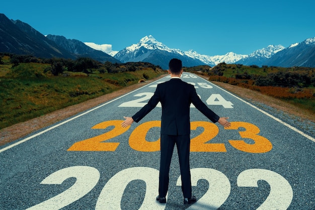 El viaje del nuevo año 2023 y el concepto de visión futura Empresario viajando por la carretera que conduce hacia una feliz celebración del nuevo año a principios de 2021 para un nuevo y exitoso comienzo