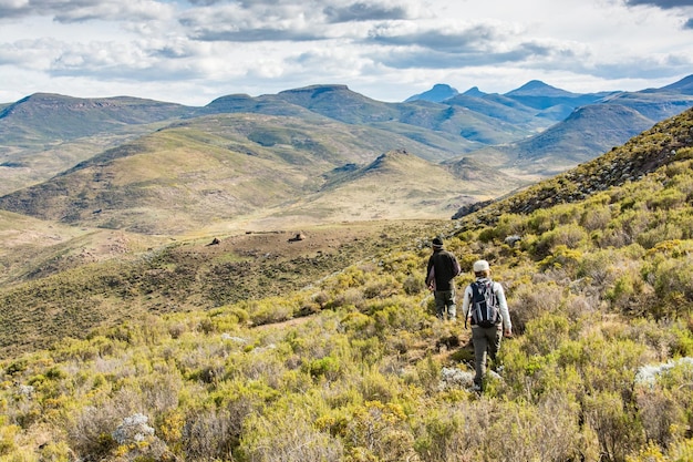 Viaje para Lesoto 2 caminhantes nas montanhas com as cabanas dos pastores à distância