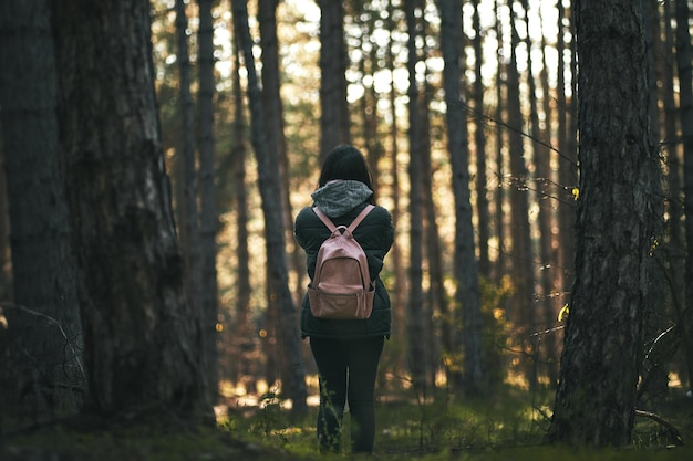 Viaje de soledad La exploración del bosque encantador de una mujer vista desde atrás Mujer de pie en el bosque Niña con mochila en el bosque