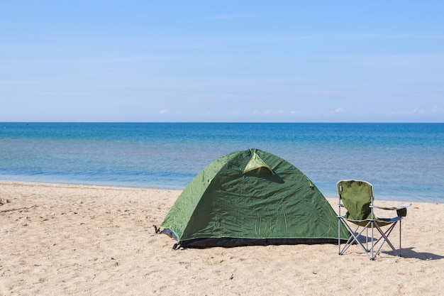 Viaje a la tienda del mar y la silla de camping en la playa.