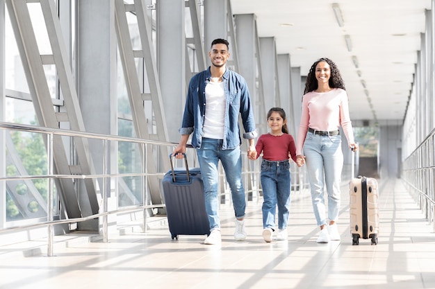 Viaje de vacaciones familia árabe feliz caminando con equipaje en la terminal del aeropuerto