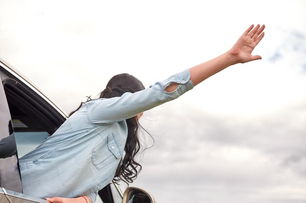 Foto viaje, viaje por carretera y concepto de personas - mujer feliz saludando con la mano asomándose por la ventana del camión