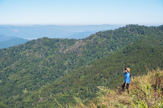 Una viajera caminando y sentada en la cima de la montaña mirando una hermosa vista