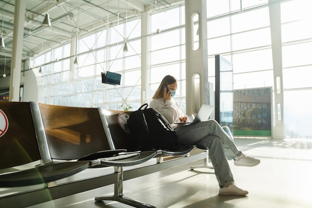 Una viajera con máscara se sienta en una silla en el vestíbulo del aeropuerto