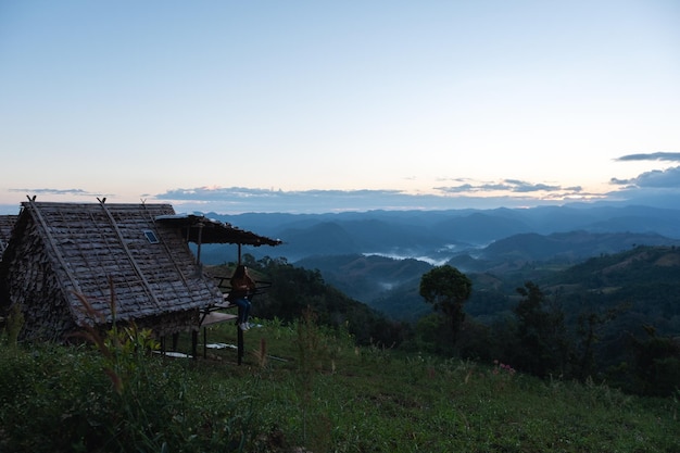 Una viajera sentada en una cabaña de madera con una hermosa vista a la montaña y la naturaleza antes del amanecer