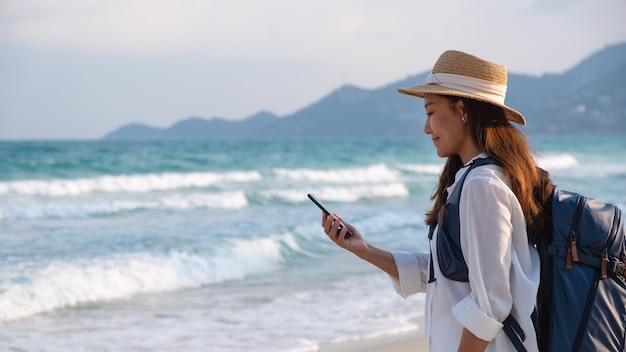 Una viajera sosteniendo y usando un teléfono móvil mientras viaja al mar