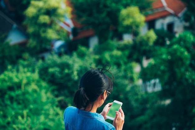 El viajero asiático de la mujer en la opinión de la parte trasera utilizó el teléfono elegante lee