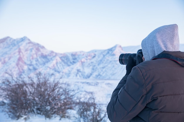 Viajero con cámara toma fotos de las montañas nevadas