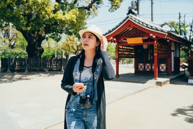 viajero caminando en el templo japonés al aire libre en el día de la luz del sol. Turista alegre usando la aplicación de mapas en línea en el teléfono celular y encontrando la dirección correcta al hotel después de visitar shitennoji osaka.