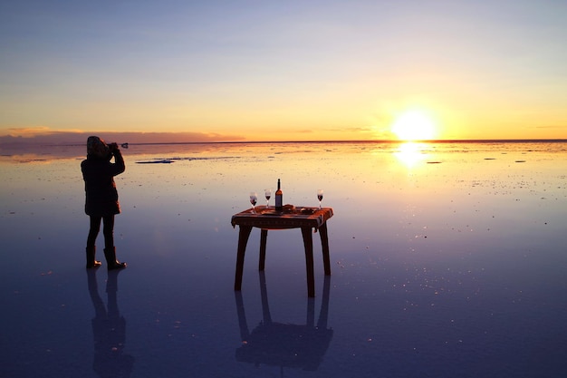 Viajero Celebrando el Efecto Espejo del Salar de Uyuni en Impresionante Puesta de Sol Bolivia