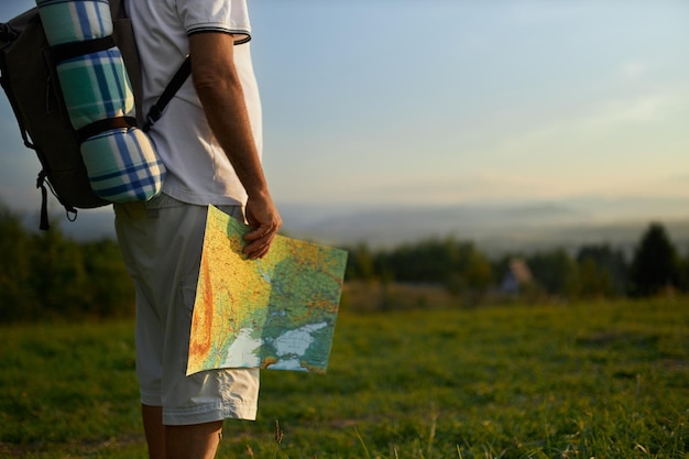 Viajero de edad avanzada que sostiene un mapa turístico mientras viaja con mochila en las montañas