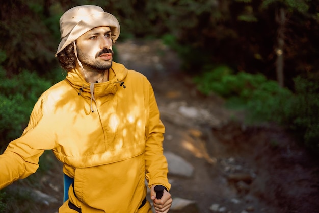 Un viajero elegante con ropa turística amarilla recorre una ruta turística de montaña en las montañas de los Cárpatos de Ucrania