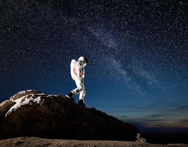 Viajero espacial caminando por la montaña bajo el cielo estrellado