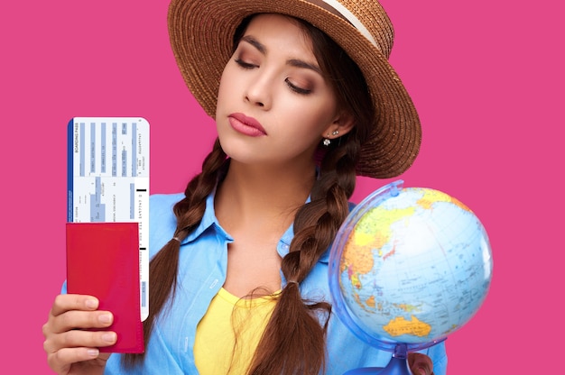 Viajero estudiante femenina con billetes de avión, pasaporte y globo, fondo aislado. Tiro del estudio. Concepto de viaje de vuelo aéreo