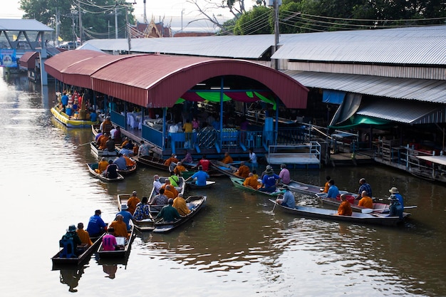 El viajero extranjero del pueblo tailandés visita y se une a la tradición del ritual del mérito y la oración ofreciendo limosnas a la procesión de monjes en un barco en el canal en Wat Sai Yai el 8 de noviembre de 2022 en Nonthaburi Tailandia