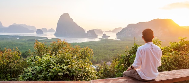 Un viajero feliz disfruta del punto de vista de la bahía de Phang Nga solo Turista sentado y relajado en Samet Nang She cerca de Phuket en el sur de Tailandia Sudeste asiático viaje y concepto de vacaciones de verano