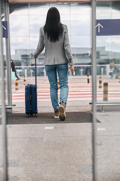 Viajero feliz mujer caucásica en la terminal del aeropuerto con equipaje
