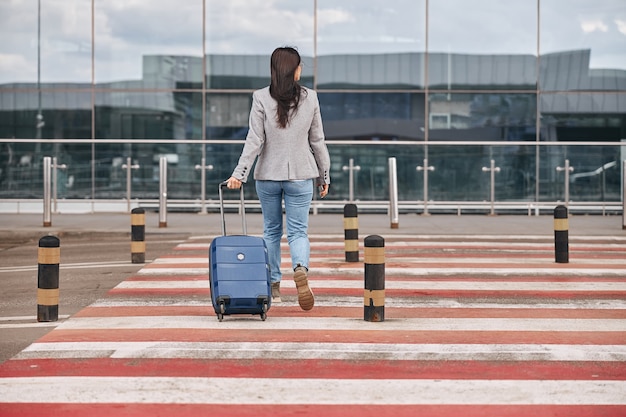 Viajero feliz mujer caucásica en la terminal del aeropuerto con equipaje