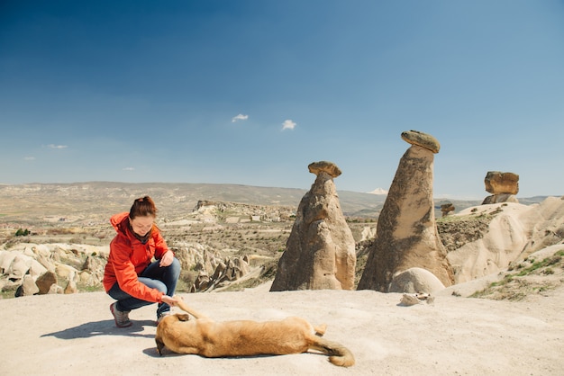 Viajero feliz mujer vinculación con perro local en chimeneas de hadas