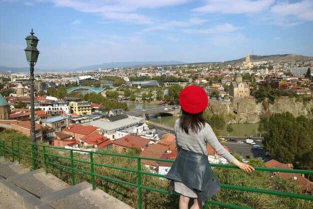 Viajero femenino impresionado por la vista panorámica con muchos de los monumentos de Tbilisi, Georgia