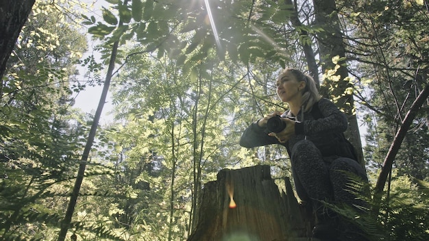 Viajero fotografiando vistas panorámicas en el bosque Una mujer caucásica disparando una bonita mirada mágica Chica toma un video fotográfico en una cámara sin espejo dslr Fotógrafo profesional de viaje con mochila al aire libre