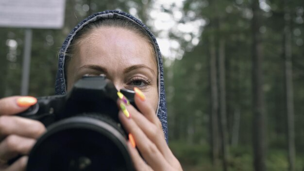 Viajero fotografiando vistas panorámicas en el bosque Una mujer caucásica disparando una mirada de cerca Chica toma un video fotográfico en una cámara sin espejo dslr Fotógrafo profesional de viaje con mochila al aire libre