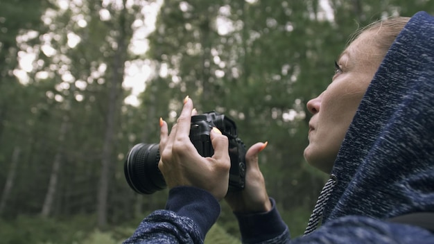 Viajero fotografiando vistas panorámicas en el bosque Una mujer caucásica disparando una mirada de cerca Chica toma un video fotográfico en una cámara sin espejo dslr Fotógrafo profesional de viaje con mochila al aire libre