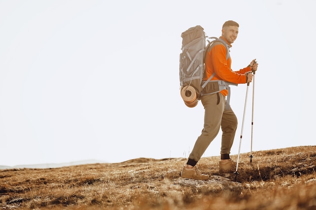 Viajero hombre con bastones de trekking subiendo la montaña