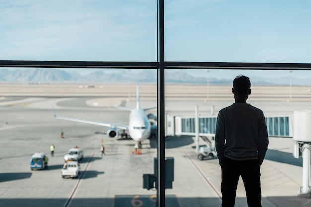 el viajero hombre con una máscara protectora está esperando el embarque en el fondo del avión. Concepto de viaje y coronavirus. Preparación del avión antes del despegue