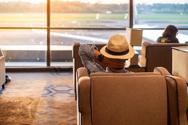 Viajero del hombre con el sombrero que mira al aeroplano en la salida del sol de la mañana