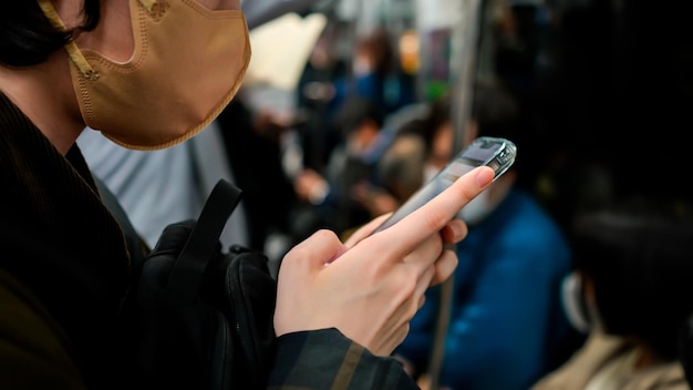 Un viajero japonés profundamente involucrado con su teléfono inteligente Una mujer usando el teléfono