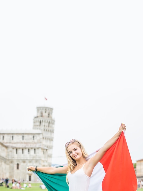 Foto viajero de joven adolescente con bandera italiana antes de la histórica torre en la ciudad de pisa - italia.