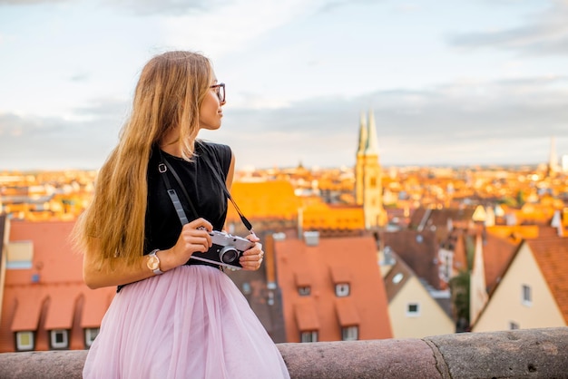 Viajero joven disfrutando de la hermosa vista del paisaje urbano sentado con cámara de fotos durante la puesta de sol en la ciudad de Nurnberg en Alemania