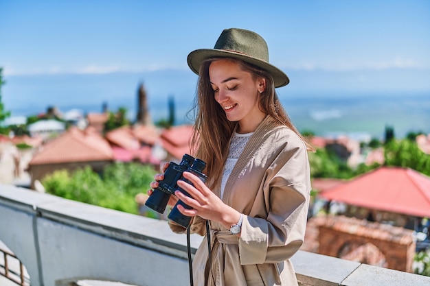 Viajero joven feliz con sombrero con binoculares durante el viaje de fin de semana de vacaciones en un día soleado