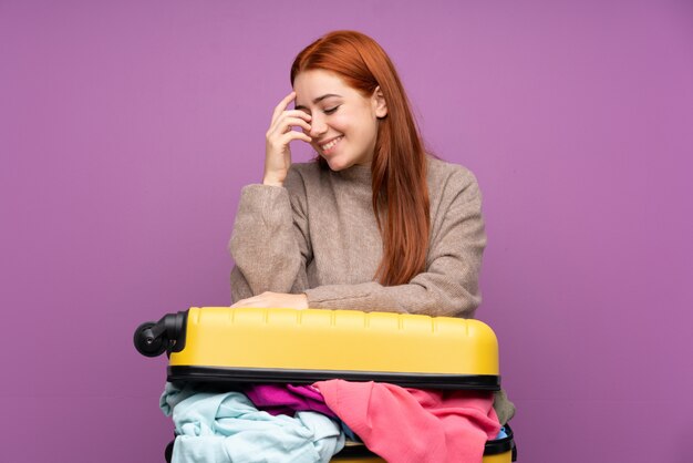 Viajero joven con una maleta llena de ropa riendo