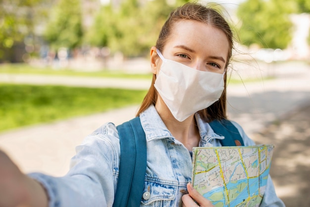 Foto viajero con máscara médica y autofoto mapa