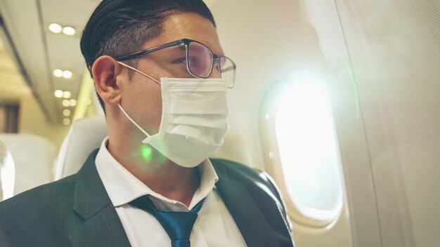 Foto viajero con mascarilla mientras viaja en avión comercial.