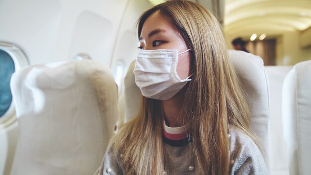 Viajero con mascarilla mientras viaja en avión comercial.