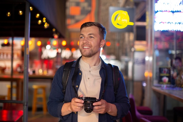 Foto viajero masculino con una cámara en un lugar local.