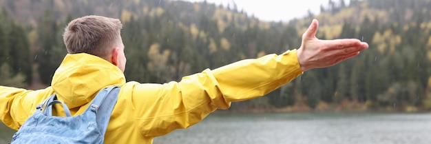 Un viajero masculino con mochila está feliz de ver la libertad de su destino de viaje, el lago y las montañas.