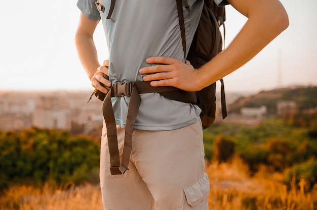 Un viajero masculino con una mochila de pie en la cima de la colina.